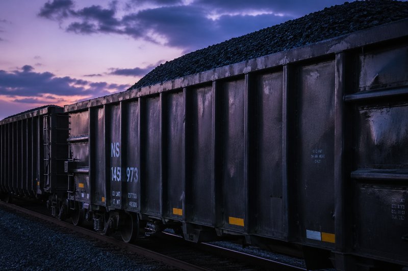 An open bulk freight car loaded with coal is standing on the tracks.