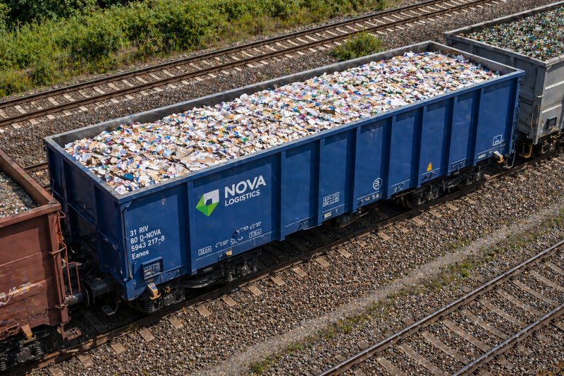 An open freight car loaded with paper rolls and recycled materials stands on the track.